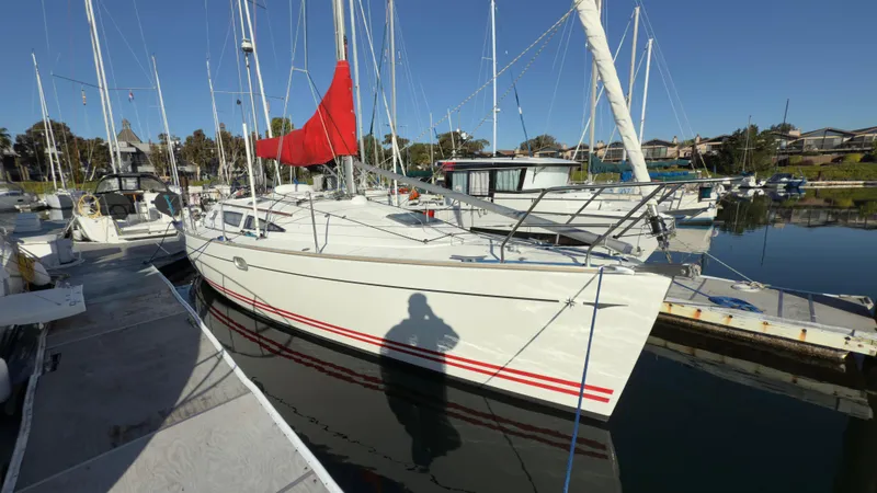 Slide: The Image of 2004 Jeanneau Sun Fast 35 sailboat docked in marina with red sail. - 2