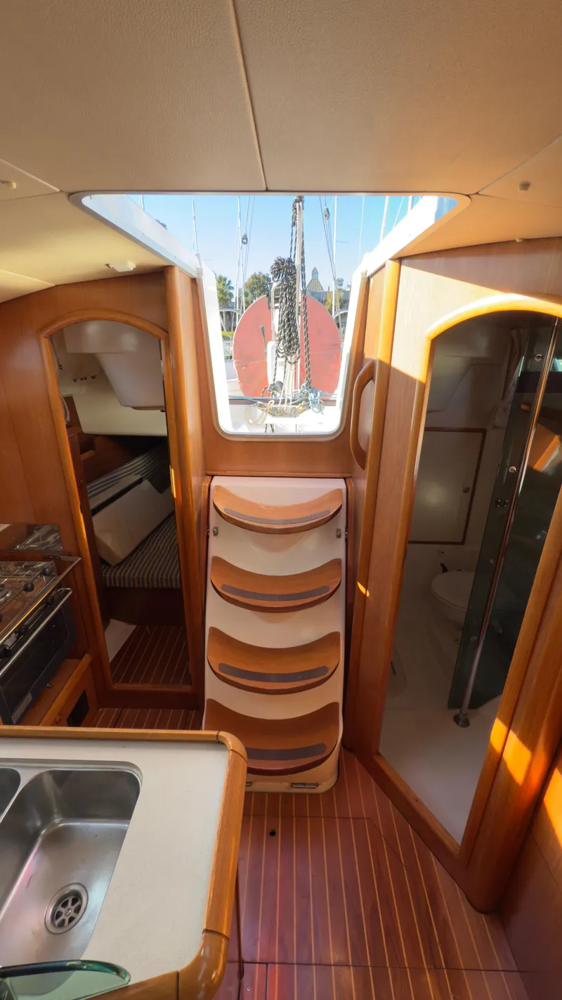 Slide: The Image of Interior of 2004 Jeanneau Sun Fast 35 sailboat, featuring wood finish and compact kitchen area. - 8