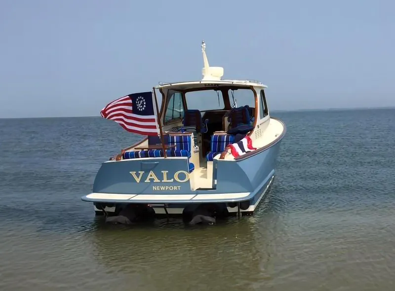 Slide: The Image of 2014 Hinckley Talaria 34 boat on water, displaying American flag, named "VALO" from Newport. - 1
