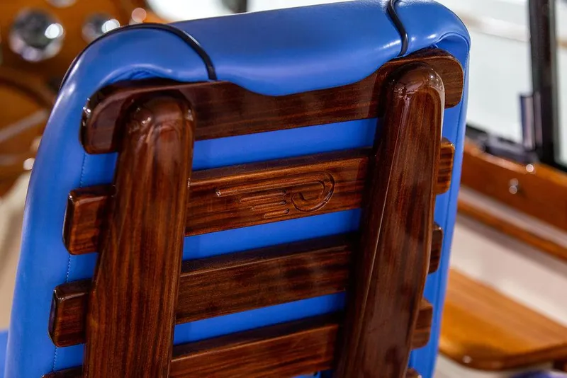 Slide: The Image of 2014 Hinckley Talaria 34 interior with blue striped seating and wooden accents. - 11