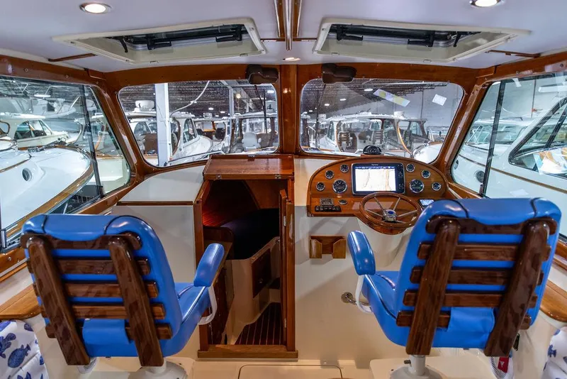 Slide: The Image of 2014 Hinckley Talaria 34 boat interior with blue-striped seating and wooden table. - 12