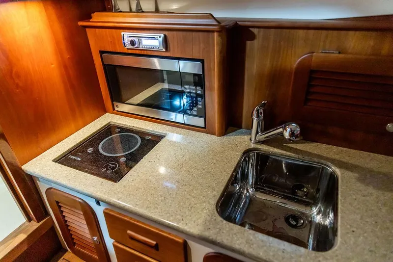 Slide: The Image of 2014 Hinckley Talaria 34 interior with blue striped seating and elegant wood accents. - 13