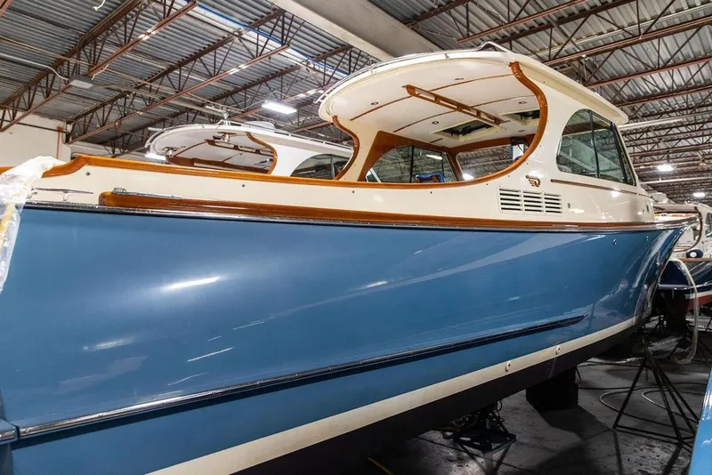 Slide: The Image of 2014 Hinckley Talaria 34 boat in a warehouse, showcasing sleek blue hull design. - 24