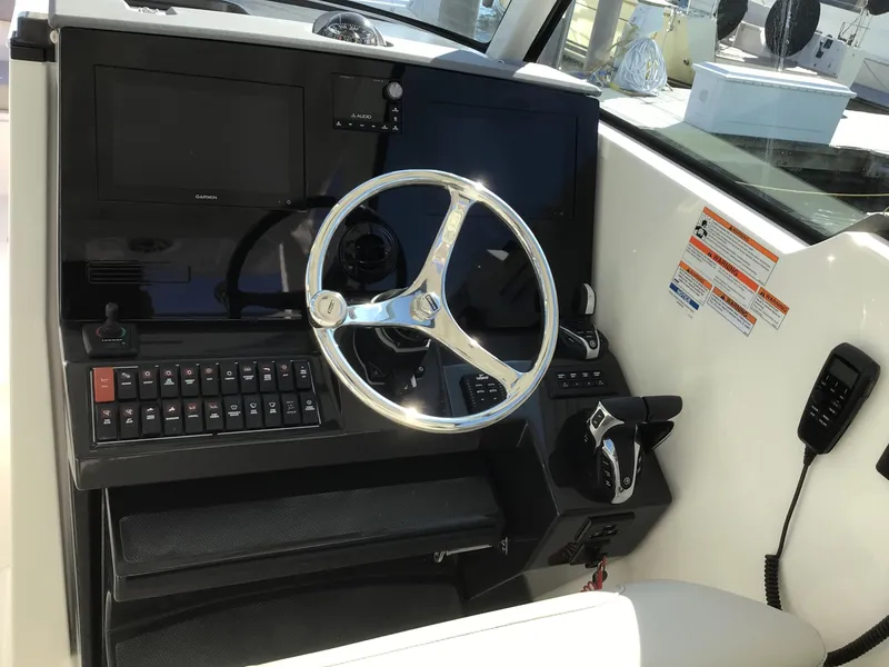 Slide: The Image of 2025 Pursuit DC 326 Dual Console boat dashboard with steering wheel and control panel. - 2