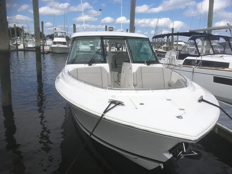 Slide: The Image of 2025 Pursuit DC 326 Dual Console boat docked in a marina under a cloudy sky. - 7