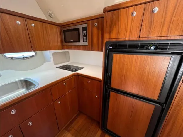 Slide: The Image of 1999 Tiara Yachts 4100 Open kitchen with wood cabinets, fridge, and microwave. - 15