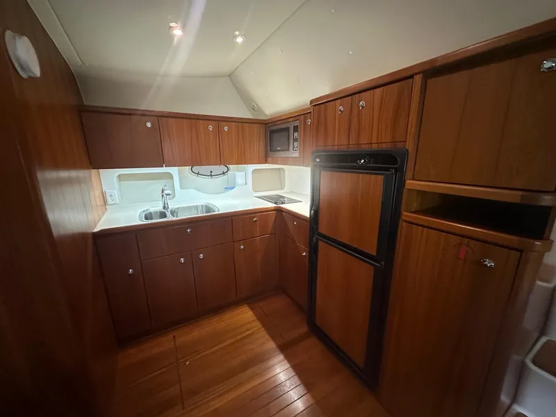 Slide: The Image of 1999 Tiara Yachts 4100 Open kitchen with wooden cabinets, sink, stove, and refrigerator. - 22