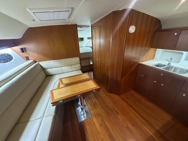 Slide: The Image of 1999 Tiara Yachts 4100 Open interior with wood paneling, kitchenette, and seating area. - 24