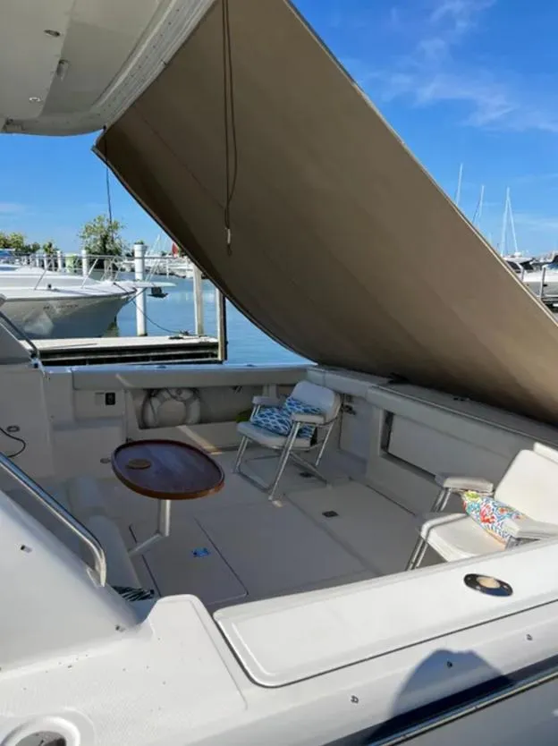 Slide: The Image of 1999 Tiara Yachts 4100 Open with canopy, docked, featuring seating and table. - 8