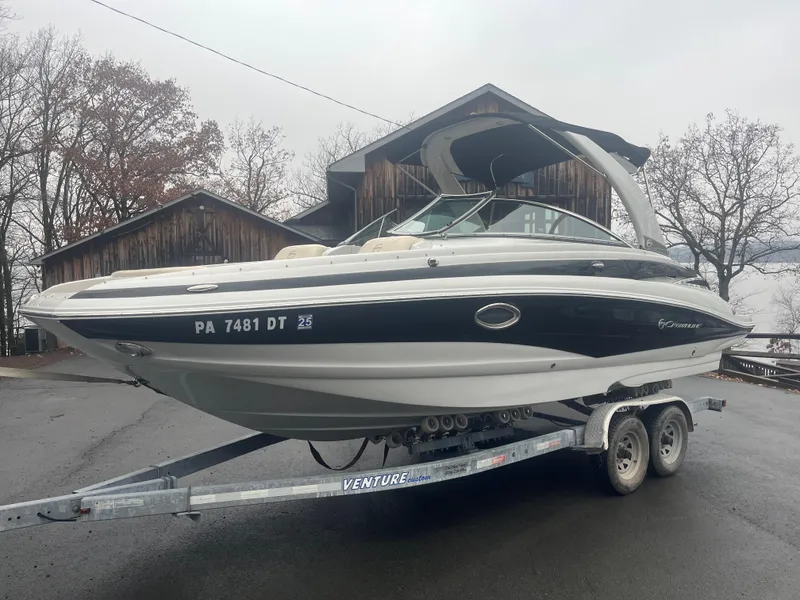 Slide: The Image of 2017 Crownline Eclipse E4 boat on trailer, parked outdoors near wooden building. - 2