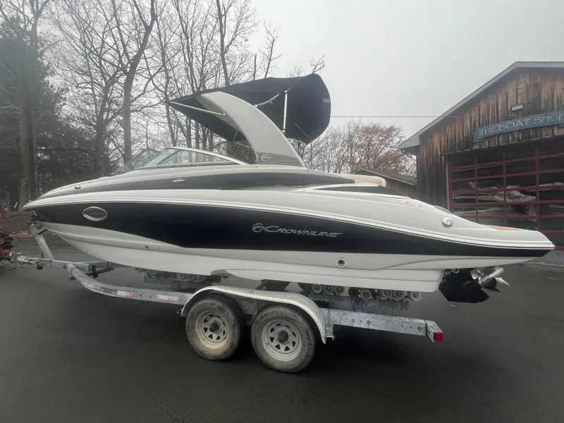 Slide: The Image of 2017 Crownline Eclipse E4 boat on trailer, parked outdoors near a wooden building. - 3