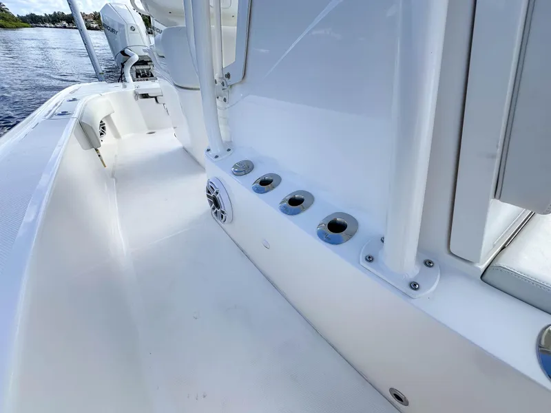 Slide: The Image of 2022 SeaVee 270Z boat interior, featuring rod holders and sleek white design by the water. - 19