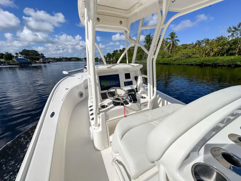 Slide: The Image of 2022 SeaVee 270Z boat interior, featuring helm and seating, cruising on a scenic waterway. - 32