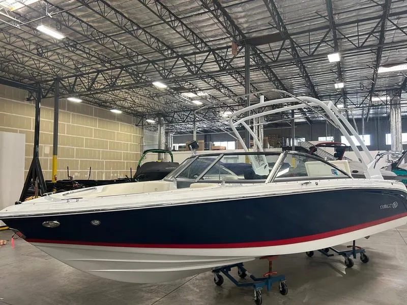 The Image of 2022 Cobalt 220S boat in a warehouse, featuring a sleek blue and white design. - 0