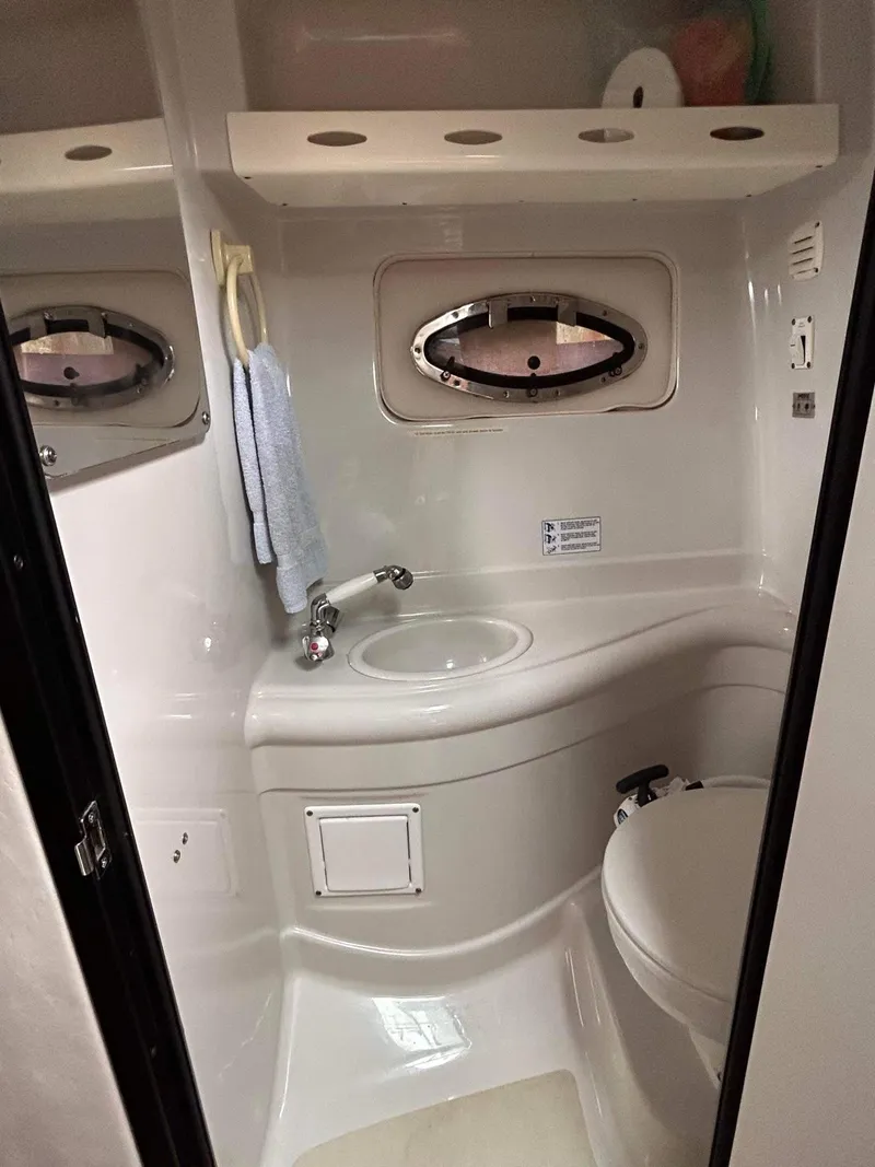Slide: The Image of 2007 Crownline 270 CR boat bathroom with sink, toilet, and porthole window. - 11