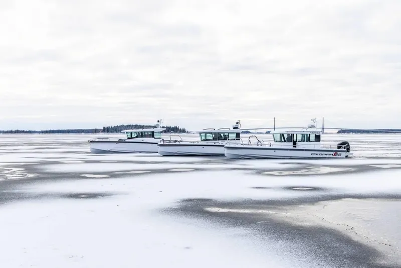 Slide: The Image of 2025 Axopar 29 XC Cross Cabin boats on icy water, overcast sky. - 3