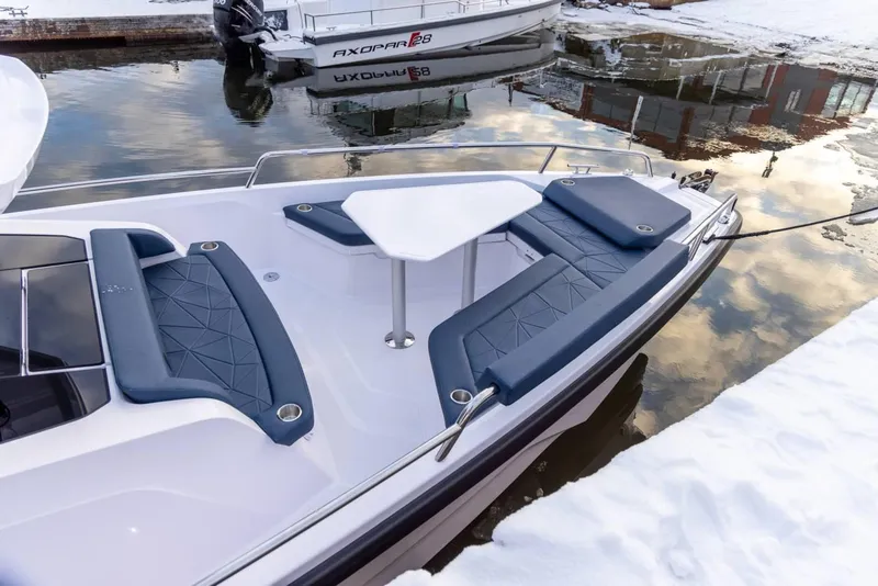 Slide: The Image of 2025 Axopar 29 XC Cross Cabin boat with seating and table, docked in snowy surroundings. - 7