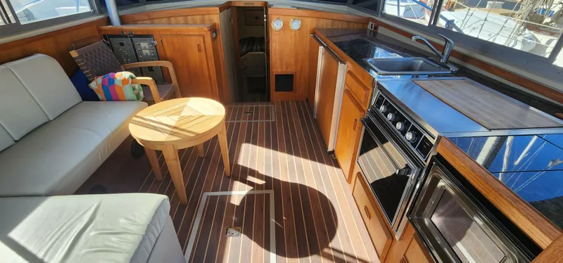 Slide: The Image of 1985 Bertram 33 Flybridge Cruiser interior with wood finish, kitchenette, and seating area. - 11