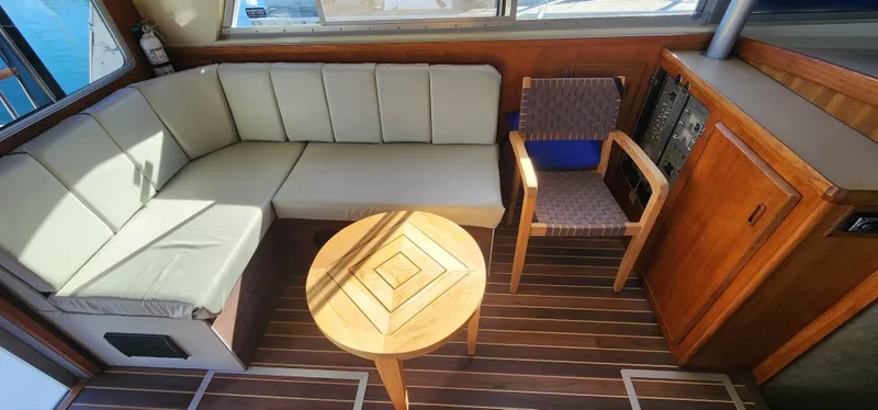 Slide: The Image of 1985 Bertram 33 Flybridge Cruiser interior with beige seating, wooden table, and chair. - 13