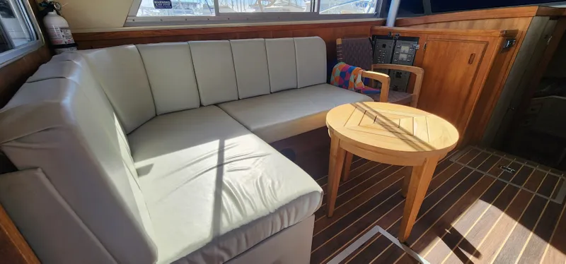 Slide: The Image of 1985 Bertram 33 Flybridge Cruiser interior with cushioned seating and wooden table. - 14