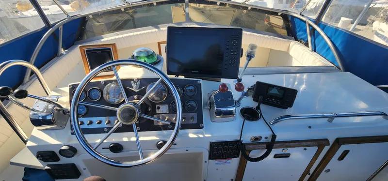 Slide: The Image of 1985 Bertram 33 Flybridge Cruiser helm with steering wheel, gauges, and navigation equipment. - 2
