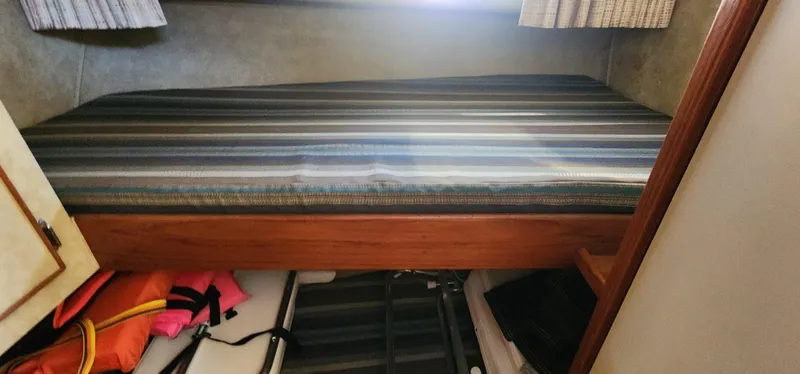 Slide: The Image of Bertram 33 Flybridge Cruiser 1985 cabin with striped bed and storage area below. - 20