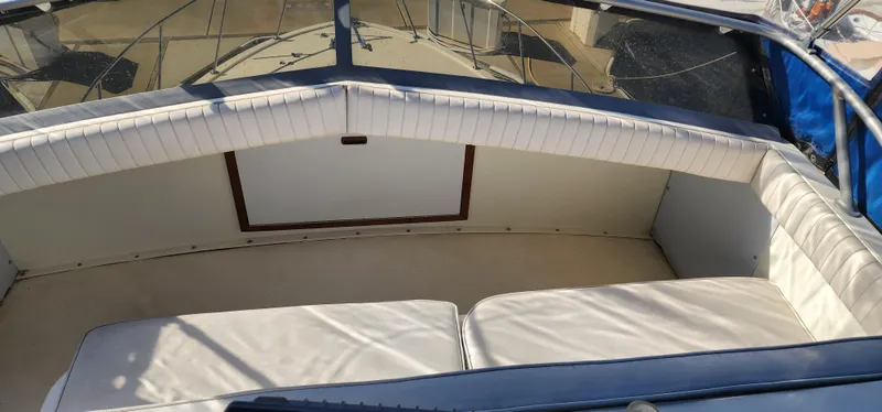 Slide: The Image of 1985 Bertram 33 Flybridge Cruiser interior with cushioned seating and windshield. - 8