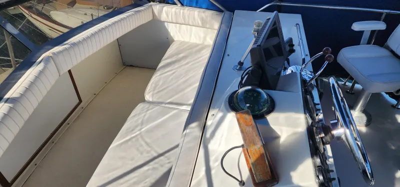 Slide: The Image of 1985 Bertram 33 Flybridge Cruiser helm with white seating and navigation equipment. - 9