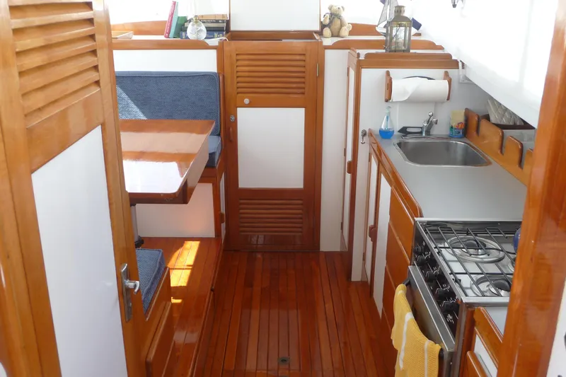 Slide: The Image of 1976 Roughwater 35 Pilothouse interior with wooden finishes, kitchenette, and dining area. - 7