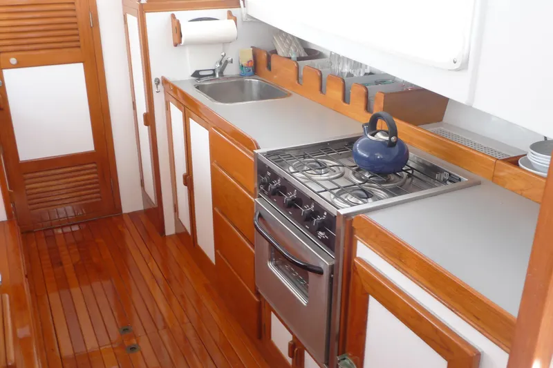 Slide: The Image of 1976 Roughwater 35 Pilothouse kitchen with stove, sink, and wooden cabinetry. - 8