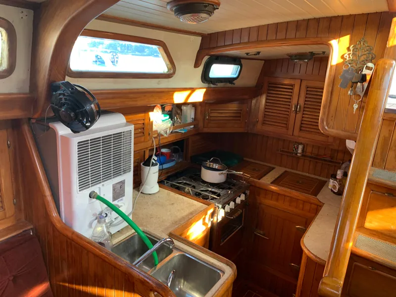 Slide: The Image of 1983 Liberty Center Cockpit yacht interior with wooden cabinetry and compact kitchen setup. - 15