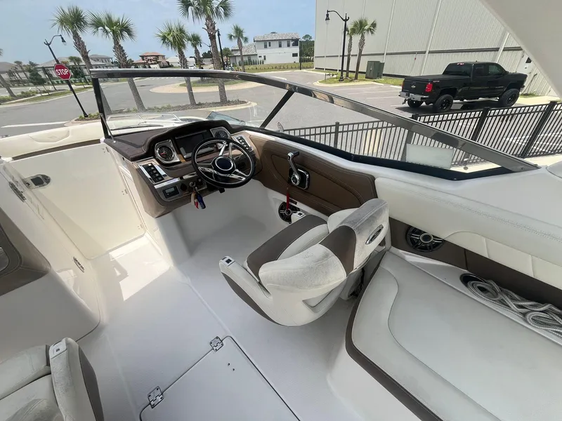 Slide: The Image of 2013 Chaparral 257 SSX boat interior with steering wheel and seating, parked near palm trees. - 27