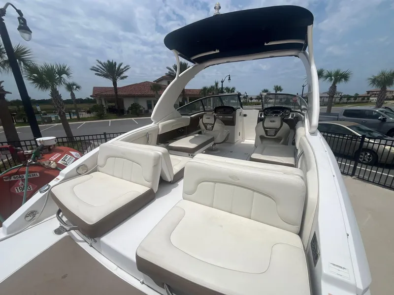 Slide: The Image of 2013 Chaparral 257 SSX boat with white seating and black canopy, docked outdoors. - 41