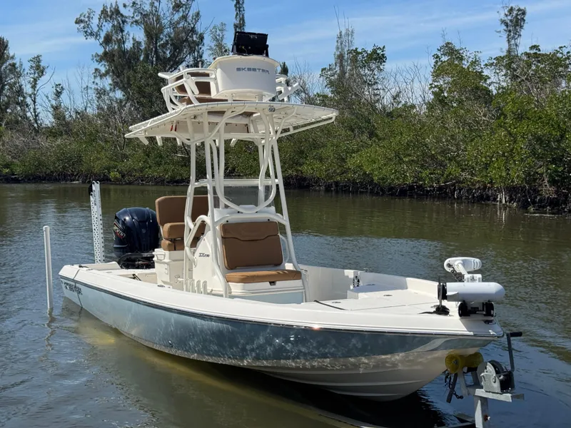 The Image of 2022 Skeeter SX230 boat on calm water, featuring elevated seating and lush greenery backdrop. - 1