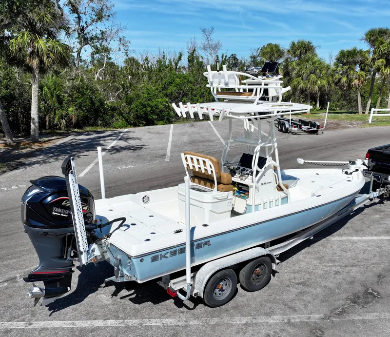 Slide: The Image of 2022 Skeeter SX230 boat on trailer, parked outdoors with trees in background. - 12