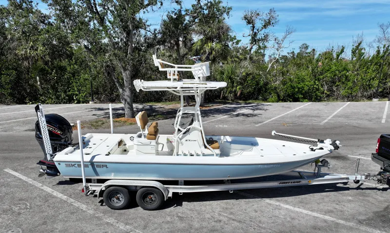 Slide: The Image of 2022 Skeeter SX230 boat on trailer in parking lot, surrounded by trees. - 14