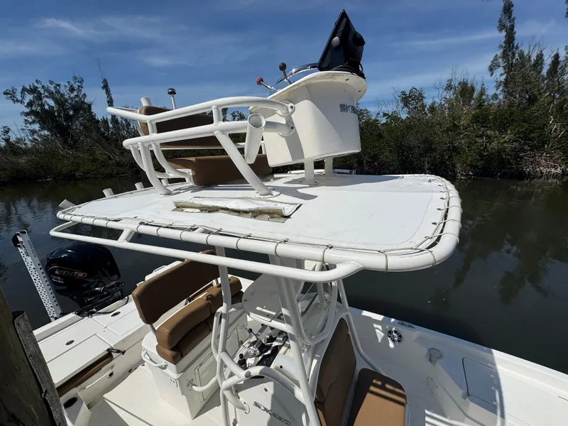 Slide: The Image of 2022 Skeeter SX230 boat with elevated helm, docked near lush greenery. - 15