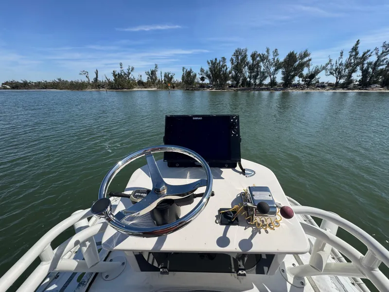 Slide: The Image of 2022 Skeeter SX230 boat dashboard with steering wheel and electronics on a calm lake. - 21