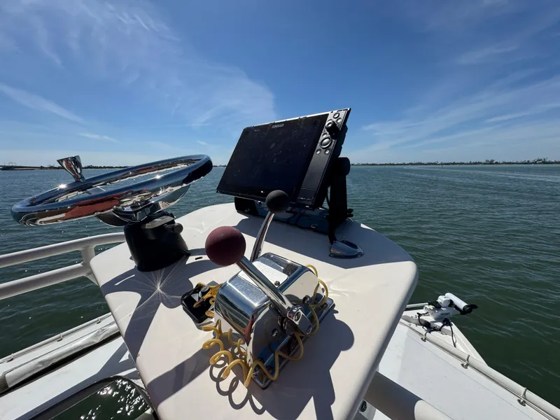 Slide: The Image of 2022 Skeeter SX230 boat helm with steering wheel and navigation system on open water. - 22