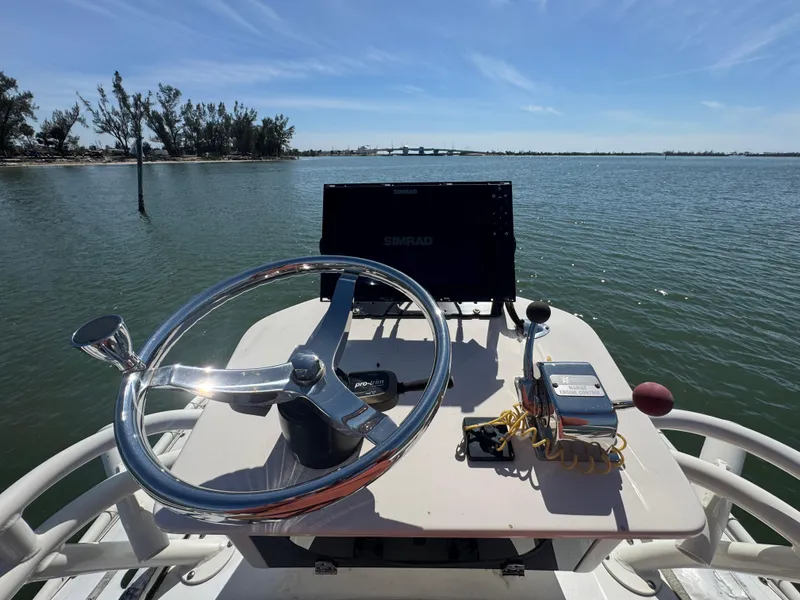 Slide: The Image of 2022 Skeeter SX230 boat helm with steering wheel and navigation equipment on a sunny day. - 23