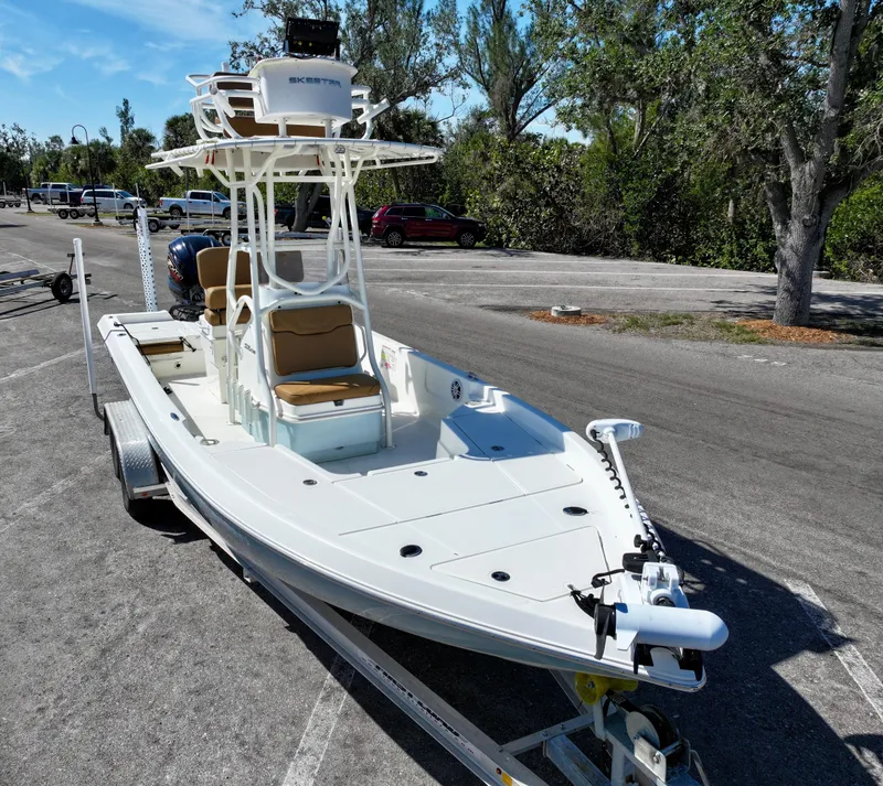 Slide: The Image of 2022 Skeeter SX230 boat on trailer in parking lot, surrounded by trees. - 3