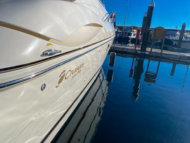 Slide: The Image of 2003 Cruisers Yachts 3275 Express docked, reflecting on calm water under clear blue sky. - 11