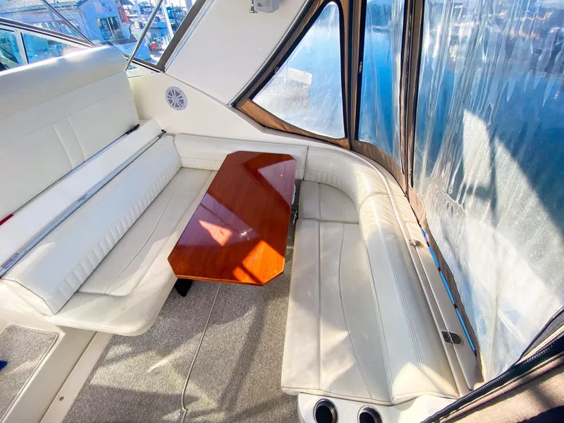 Slide: The Image of Interior of 2003 Cruisers Yachts 3275 Express with white seating and wooden table. - 13