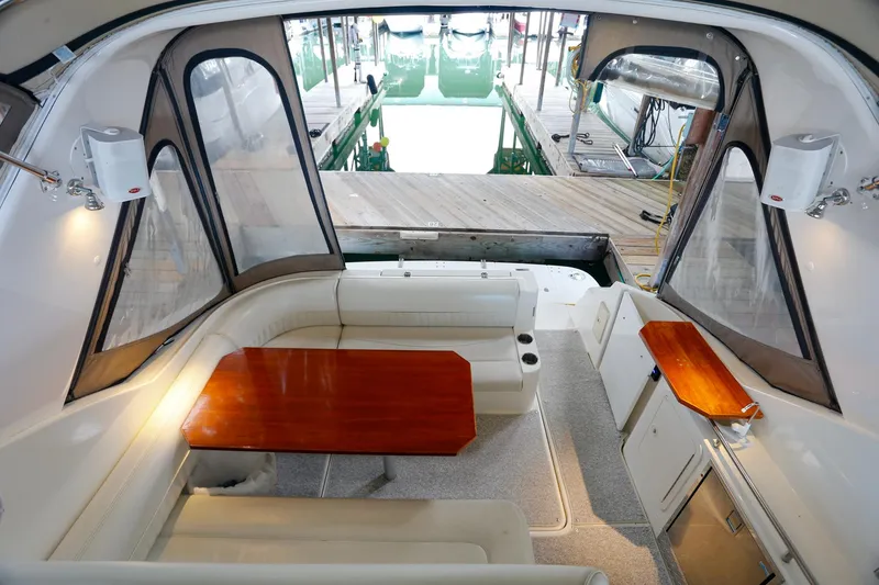 Slide: The Image of 2003 Cruisers Yachts 3275 Express interior with seating and wooden table, dockside view. - 20