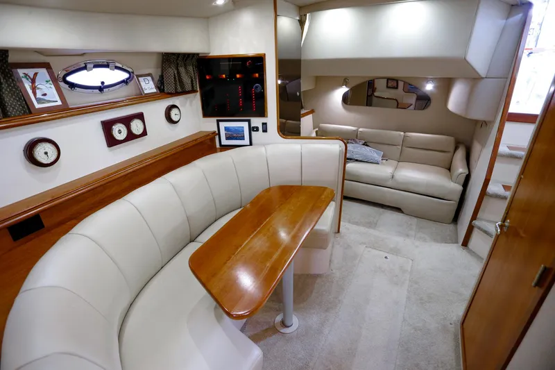 Slide: The Image of Interior of 2003 Cruisers Yachts 3275 Express, featuring a cozy seating area and elegant wood finishes. - 29