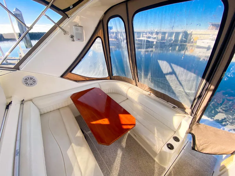 Slide: The Image of 2003 Cruisers Yachts 3275 Express interior with white seating and wooden table. - 12