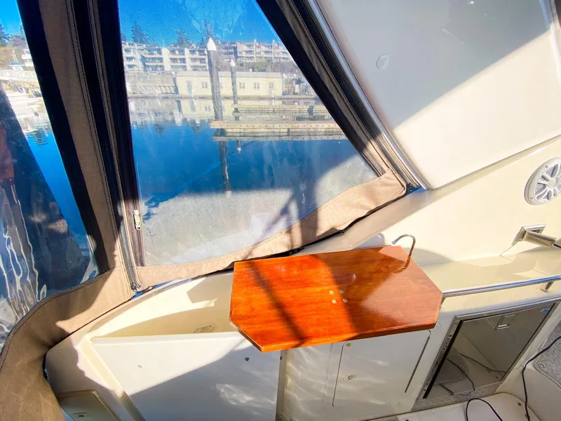 Slide: The Image of 2003 Cruisers Yachts 3275 Express interior with wooden table and marina view. - 14