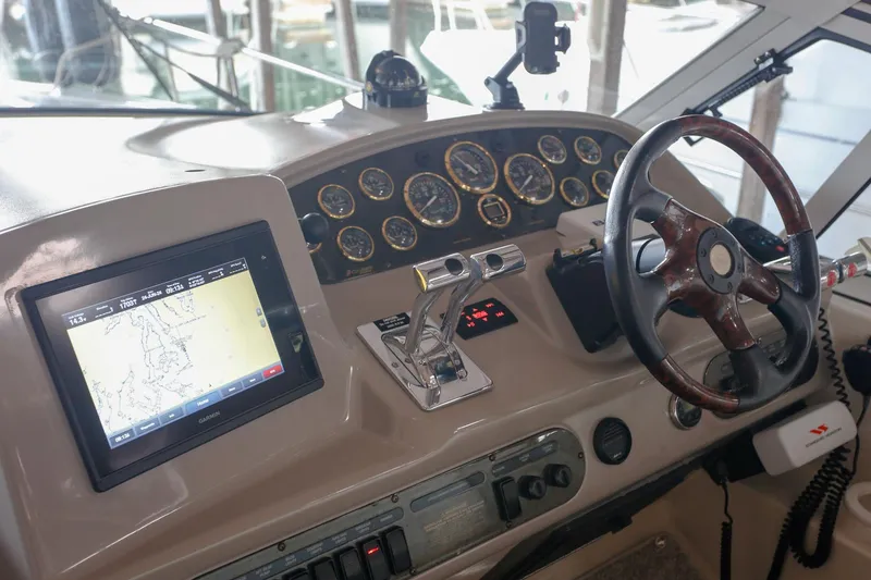Slide: The Image of 2003 Cruisers Yachts 3275 Express helm with GPS, gauges, and wooden steering wheel. - 23