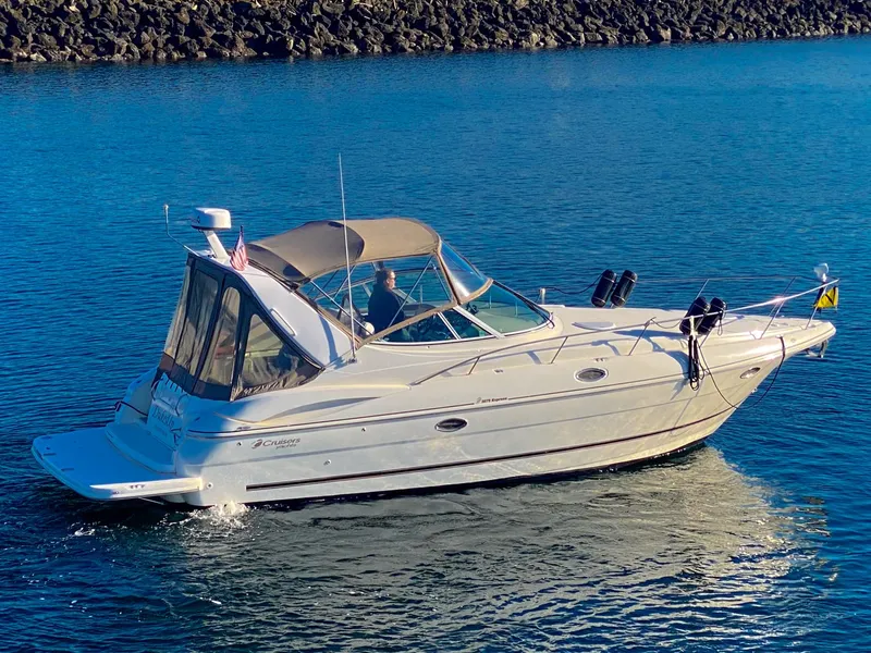 Slide: The Image of 2003 Cruisers Yachts 3275 Express boat on calm water, clear sky, rocky shoreline. - 4