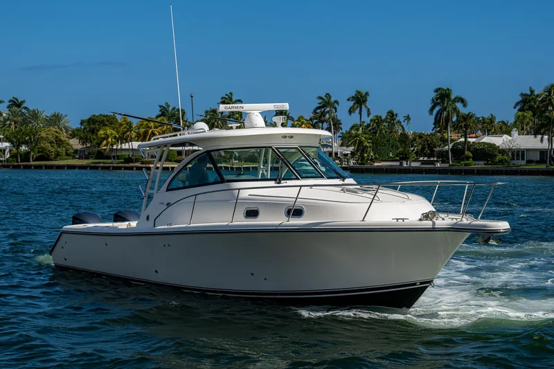Slide: The Image of 2014 Pursuit 345os boat cruising on a sunny day with palm trees in the background. - 13